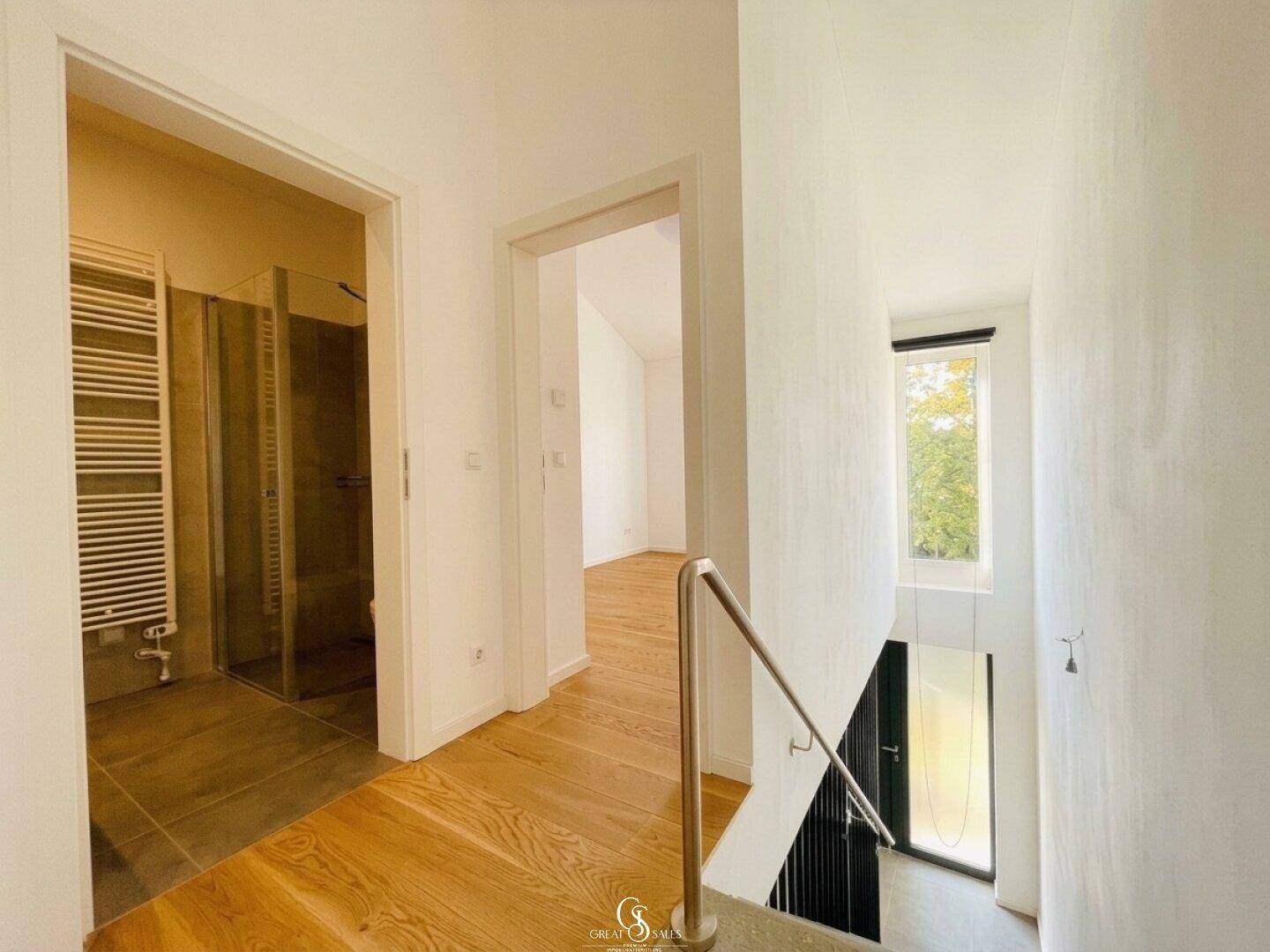Heller Flur im Obergeschoss mit Zugang zu Bad und weiteren Zimmern, ausgestattet mit Holzboden.