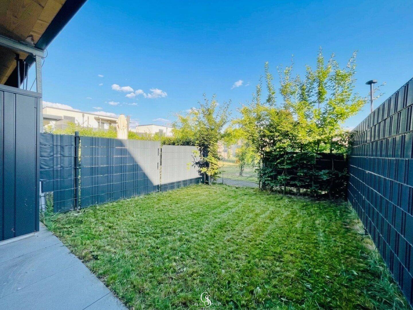 Gepflegter Gartenbereich hinter dem Reihenhaus mit Rasen und Sichtschutzzaun.