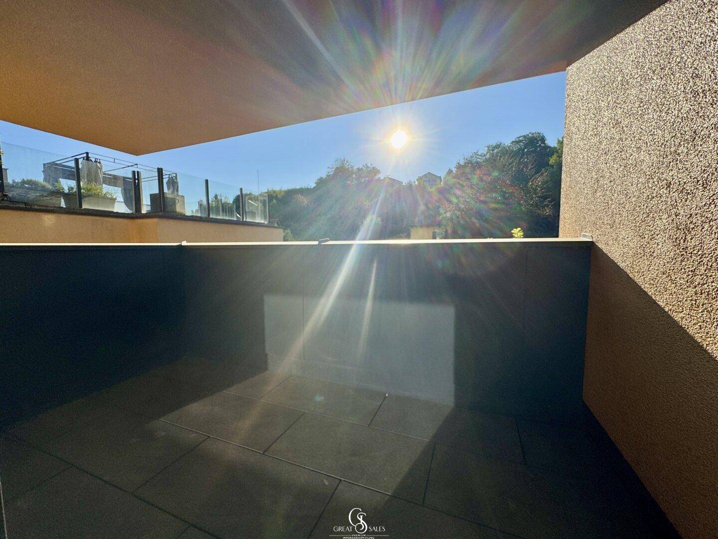 Helle Terrasse mit Fliesenboden, die von der Sonne durchflutet wird.