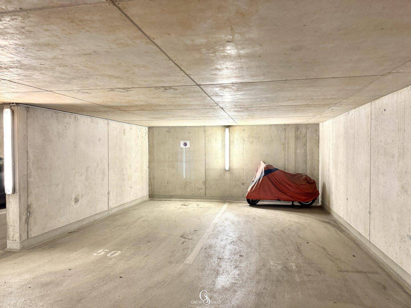 Geräumige Tiefgarage mit Betonwänden und -boden, bietet Platz für Fahrzeuge.
