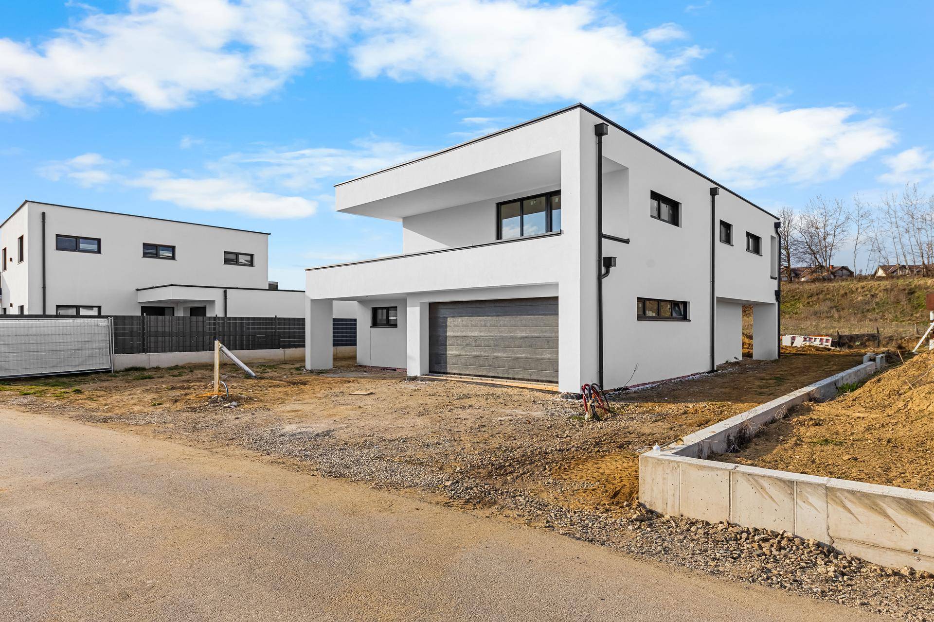 Modernes weißes Einfamilienhaus im Bau mit Flachdach und integrierter Doppelgarage.