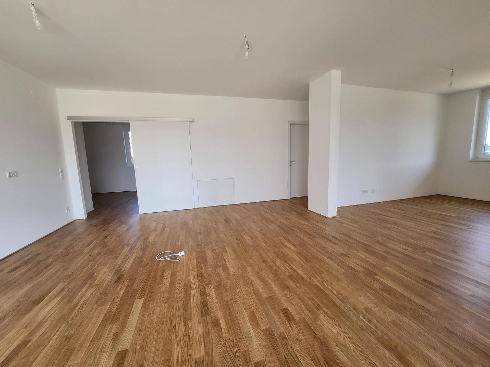 Offener Wohnbereich mit Holzboden und viel Tageslicht, ideal für individuelle Gestaltung.