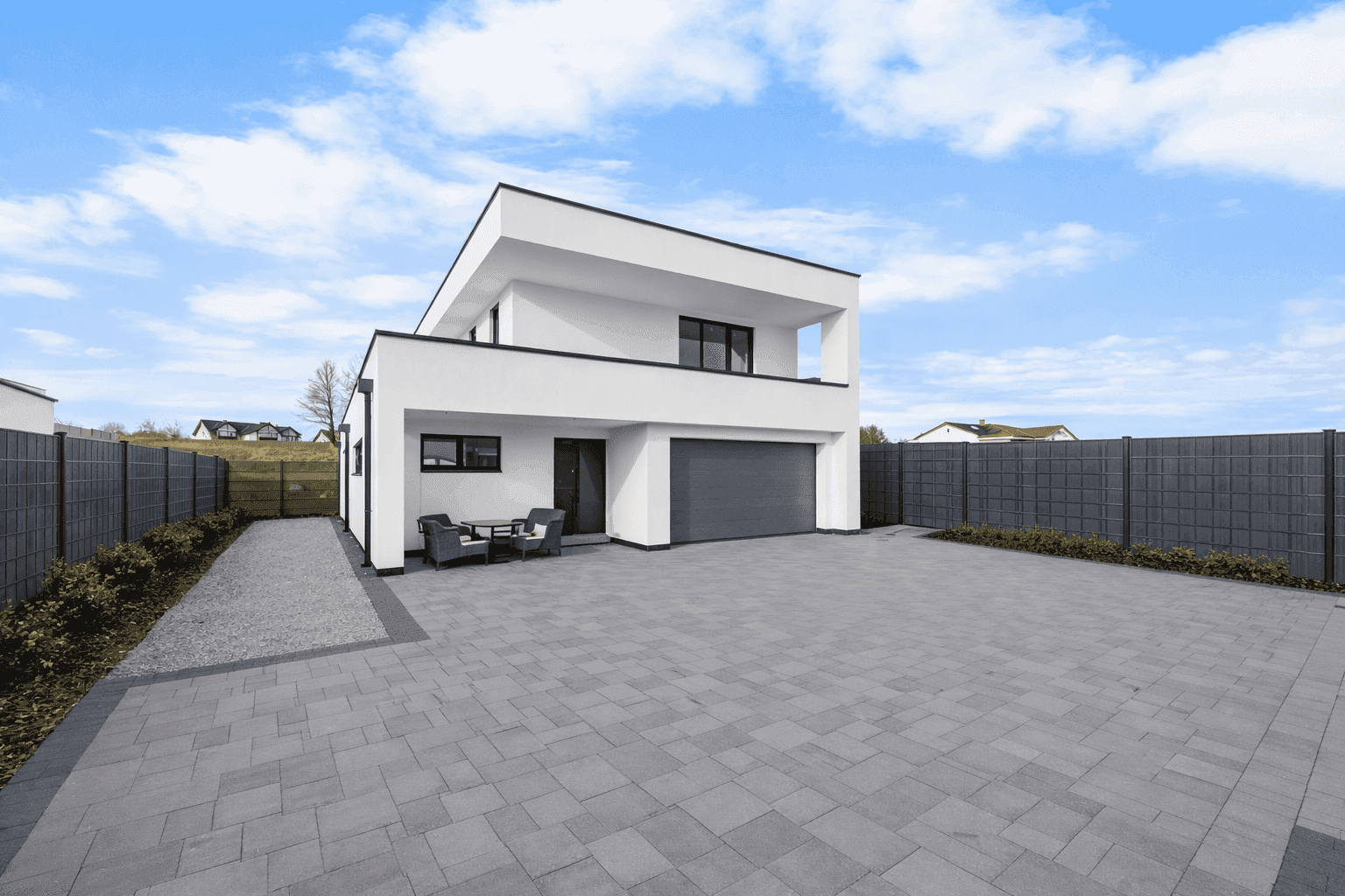 Moderne Hausfassade mit großer gepflasterter Einfahrt und integrierter Garage.