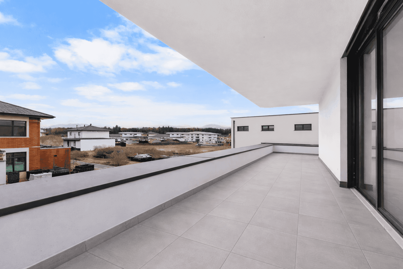 Großer, gefliester Balkon mit weitem Blick über die Umgebung und die Dächer der Nachbarschaft.