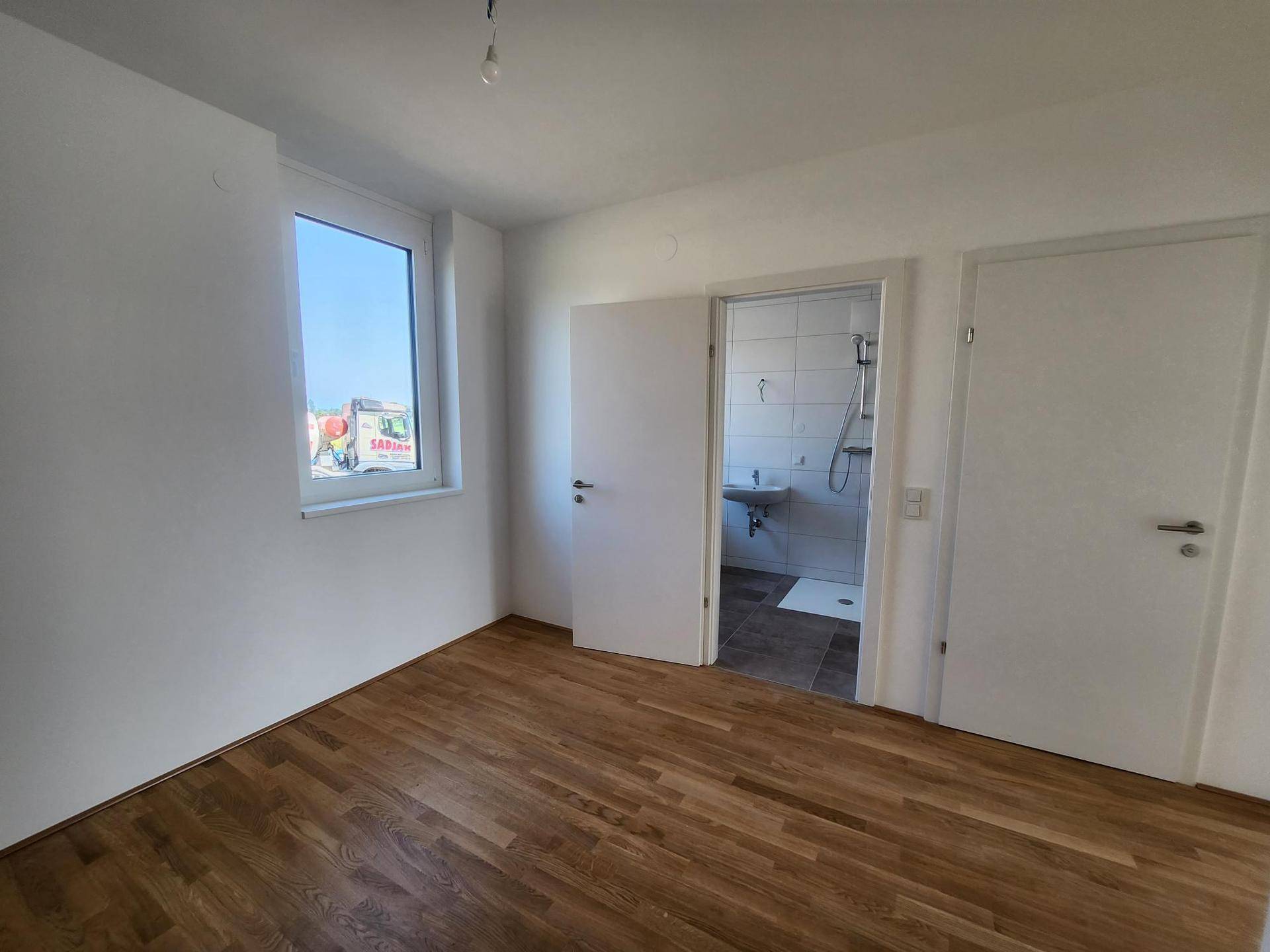 Schlafzimmer mit Holzboden und direktem Zugang zu einem angrenzenden Badezimmer.