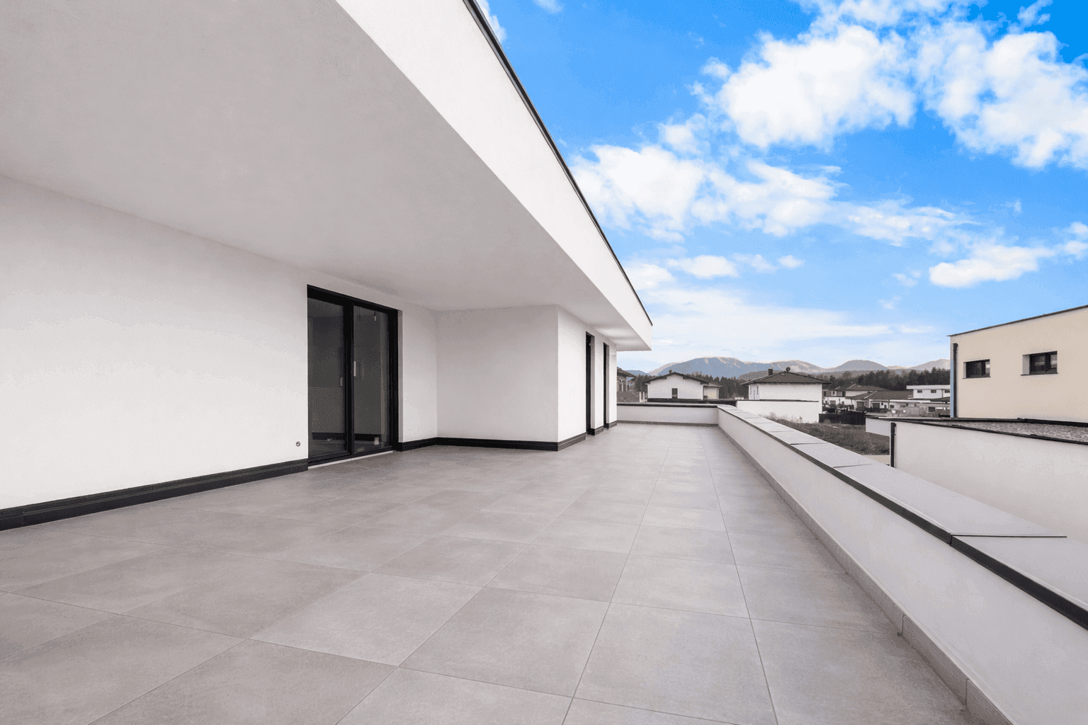 Weitläufige Dachterrasse mit Fliesenboden und Panoramablick auf die Berge und Umgebung.
