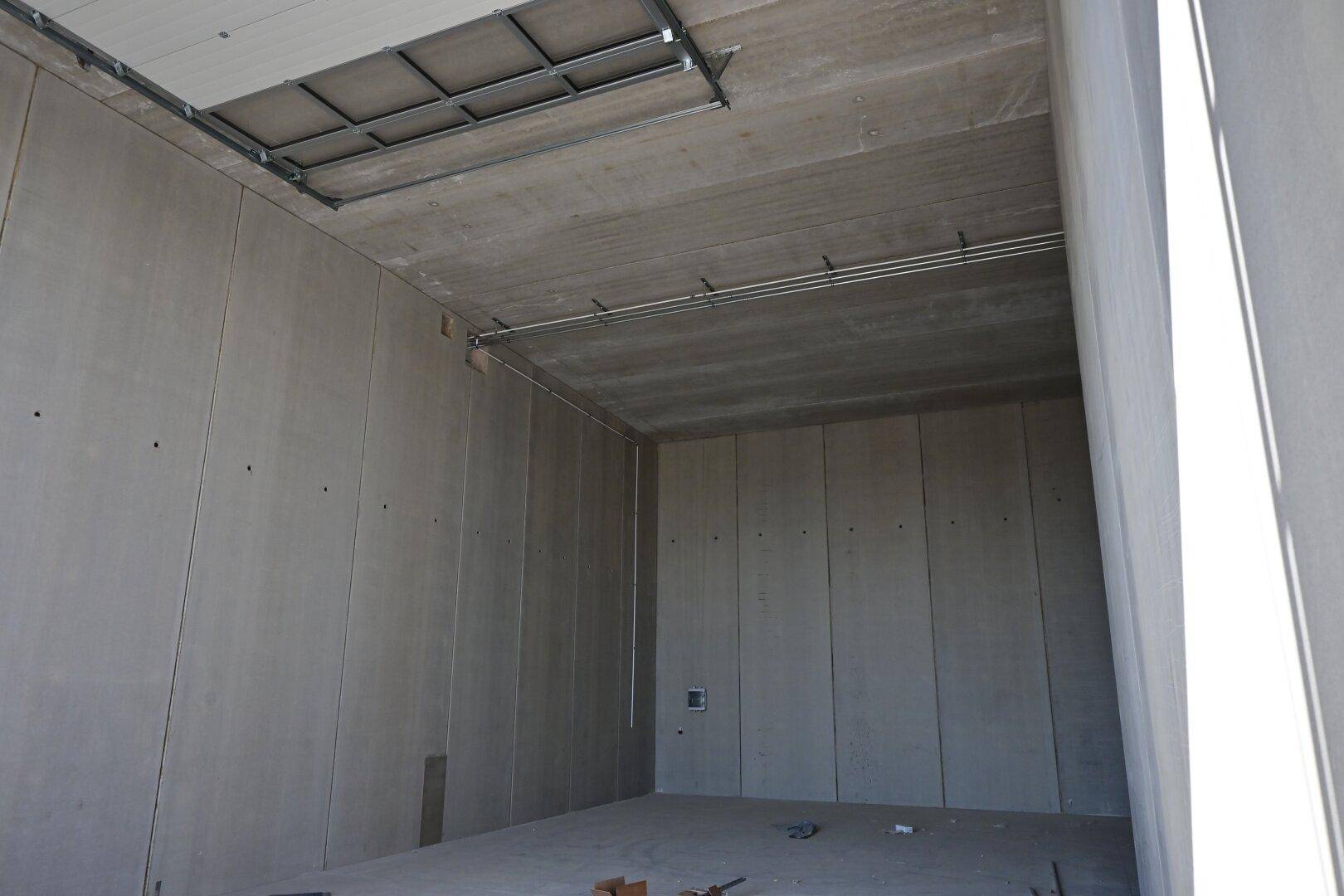 Leerer Industrieraum mit hohen Betonwänden und -decken, bereit für den Ausbau.