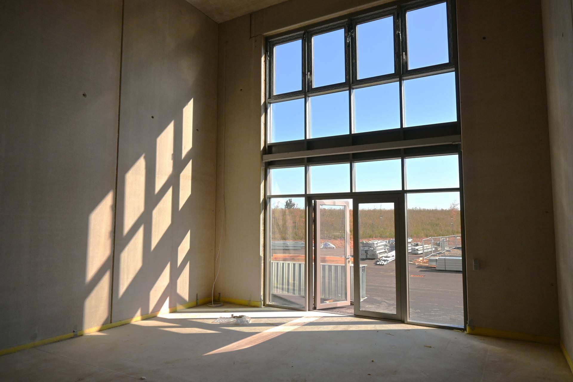 Heller Innenraum mit großer Glasfront und Zugang zum Außenbereich, noch im Bau.