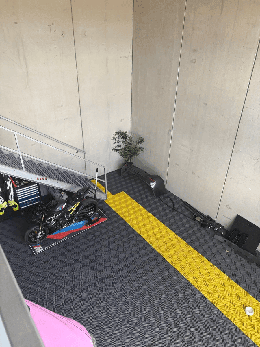 Blick von der Mezzanine-Ebene auf den Werkstattboden mit Motorrad, Treppe und industriellem Design.