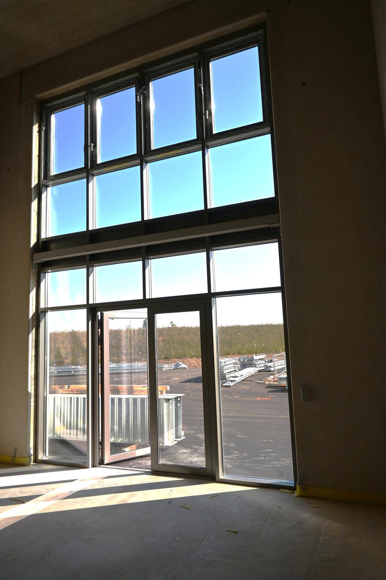 Große, bodentiefe Fenster in einem hellen, leeren Raum, der viel Tageslicht hereinlässt.