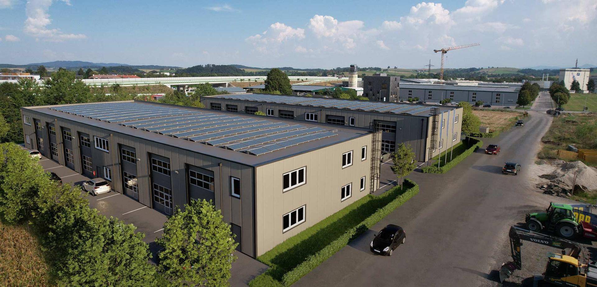 Luftaufnahme eines modernen Gewerbekomplexes mit Photovoltaikanlage auf den Dächern und umliegender Landschaft.