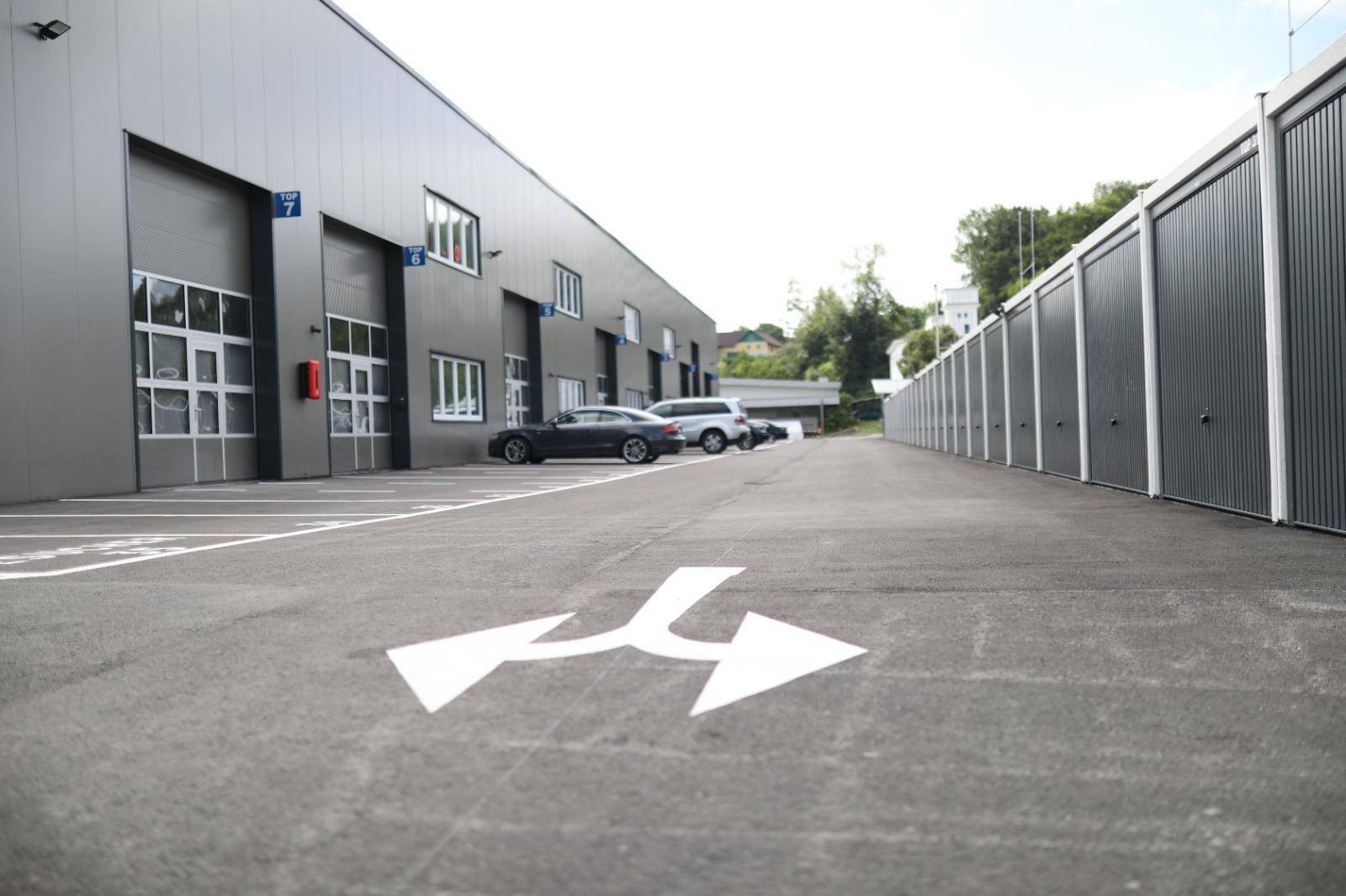 Gewerbegebäude mit Garagentoren und einer Reihe von Lagerboxen entlang einer Zufahrtsstraße.