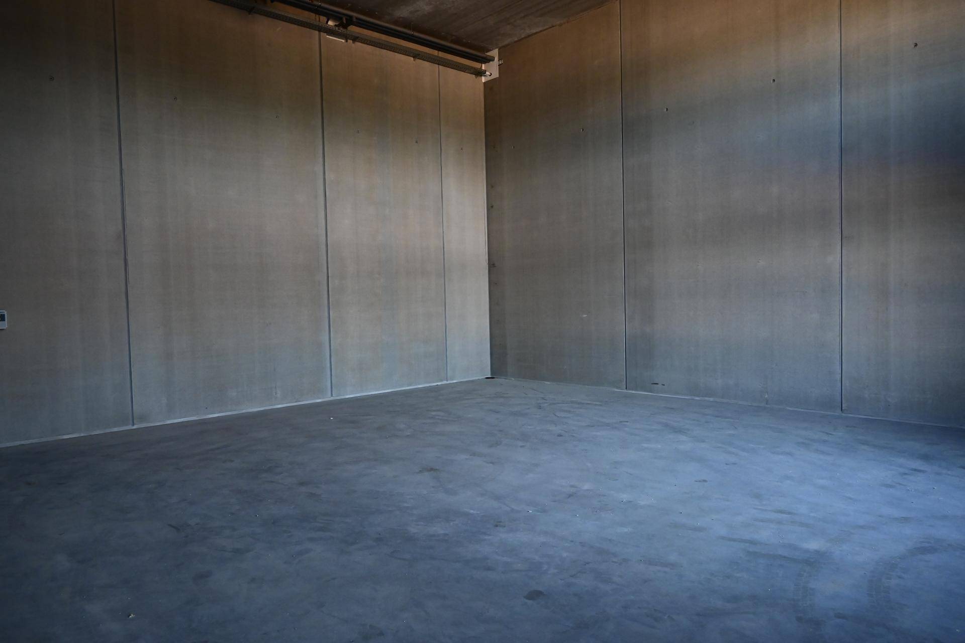Leerer Raum mit grauen Betonwänden und Betonboden, bereit für die Nutzung.