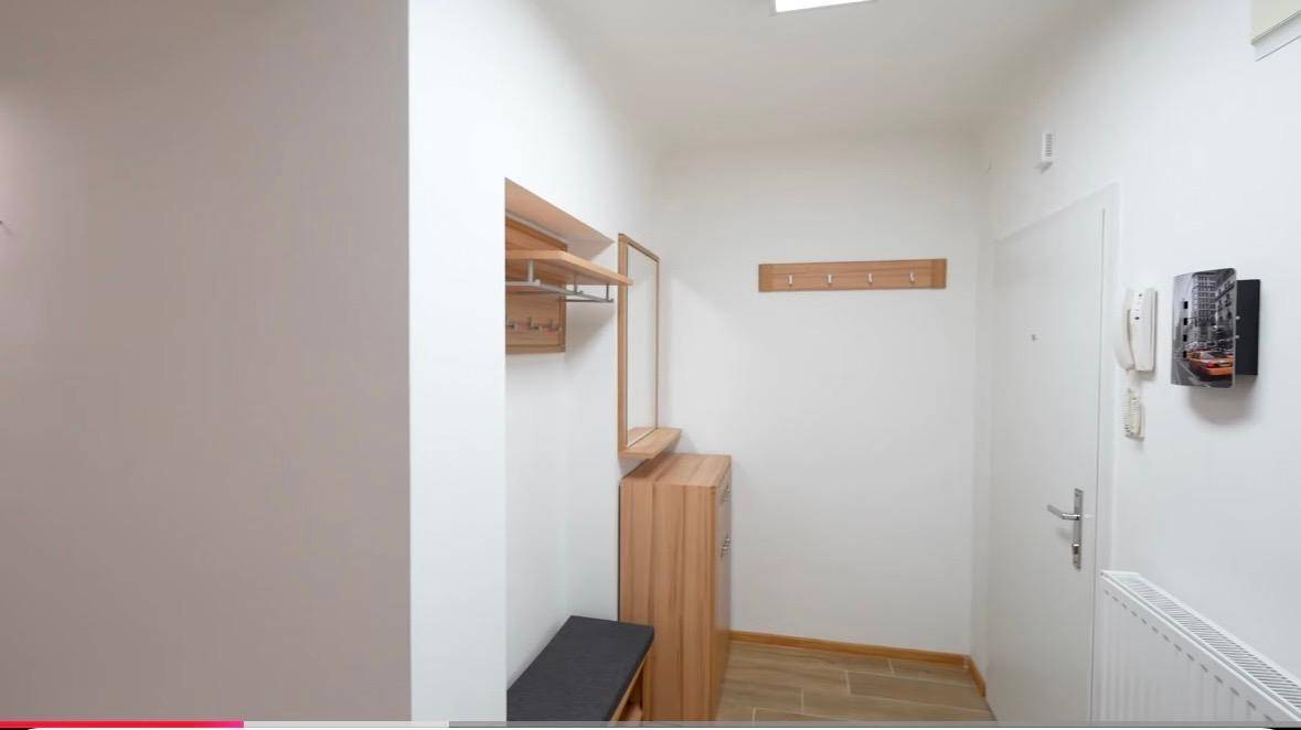 Eingangsbereich mit praktischer Holzgarderobe, Spiegel und Sitzbank, ideal für den Empfang von Gästen.