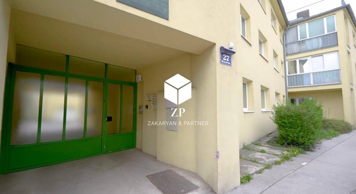 Eingangsbereich eines Gebäudes mit grüner Garagentür und der Aufschrift "ZAKARYAN & PARTNER".