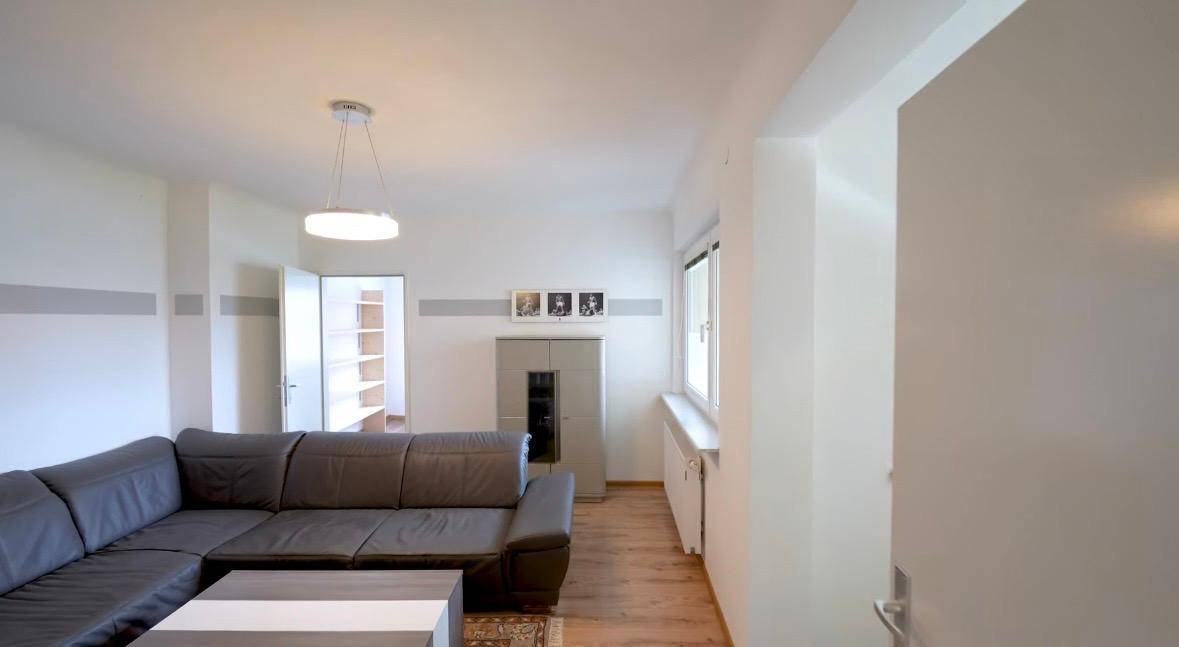 Geräumiges Wohnzimmer mit bequemer Eckcouch, Couchtisch und Fenster für angenehmes Tageslicht.