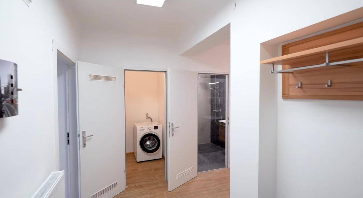 Geräumiger Flur mit Garderobe, Waschmaschine im Abstellraum und Blick in das angrenzende Badezimmer.