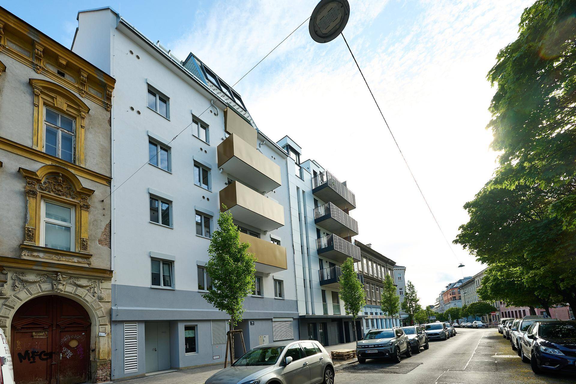 Moderne Wohngebäude mit Balkonen und großen Fenstern in einer städtischen Umgebung.