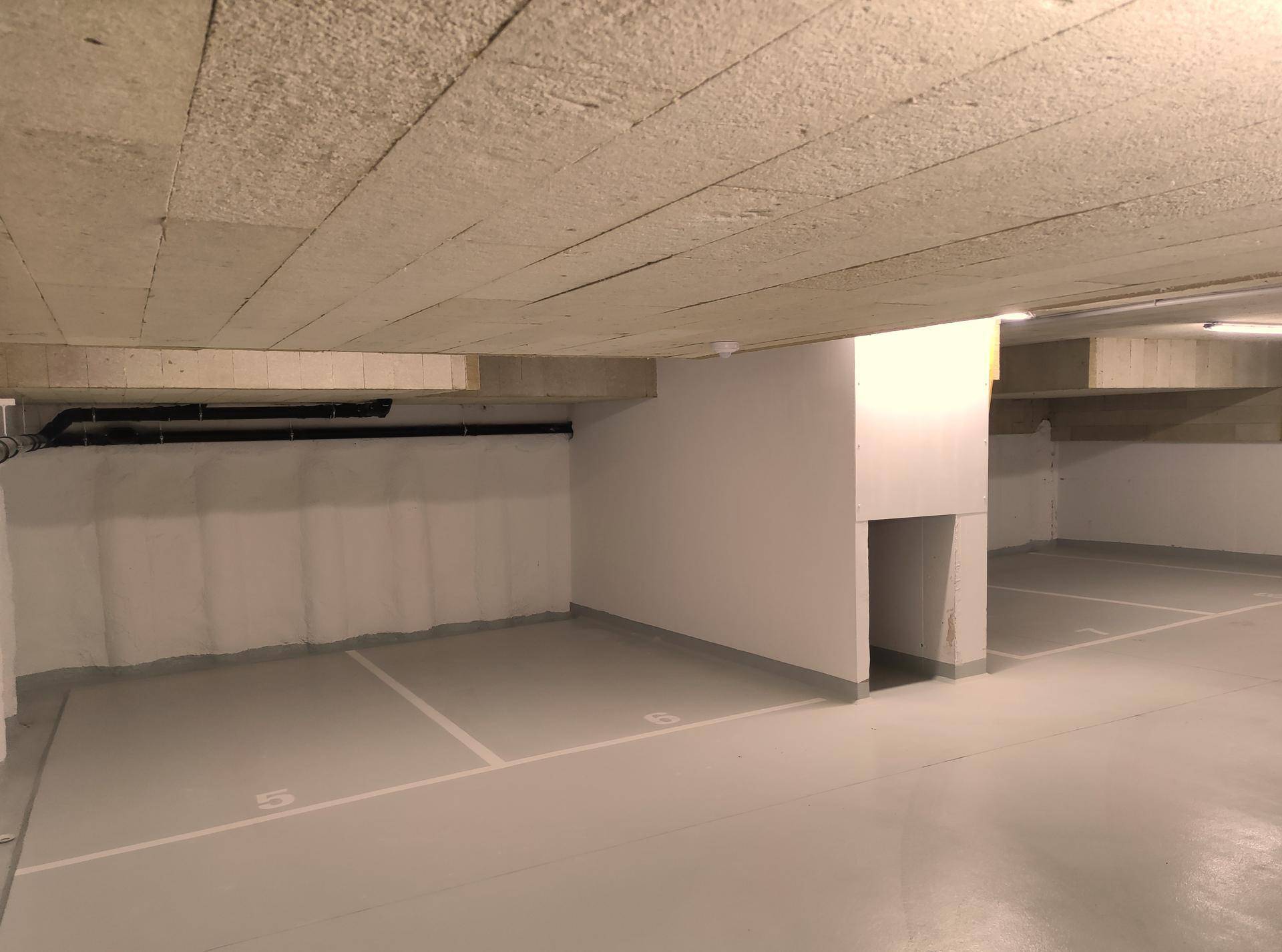 Tiefgarage mit markierten Stellplätzen und Betonwänden unter dem Gebäude.