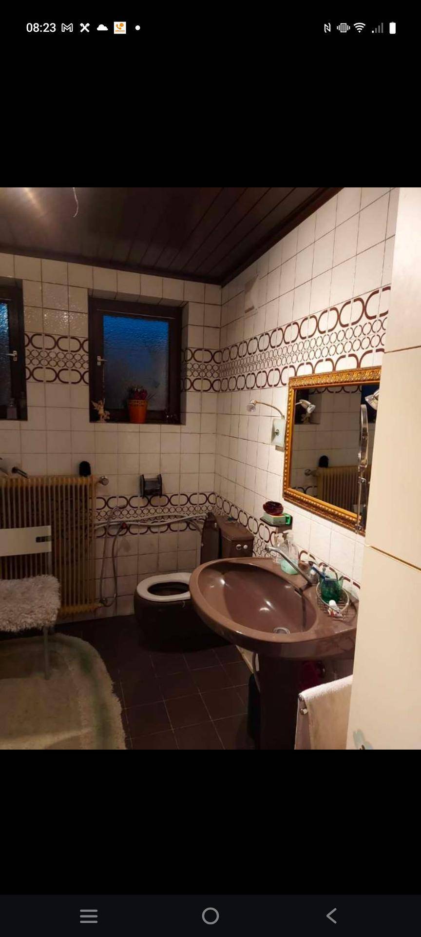 Badezimmer mit gemusterten Fliesen, Waschbecken und Toilette, ausgestattet mit einem Fenster.