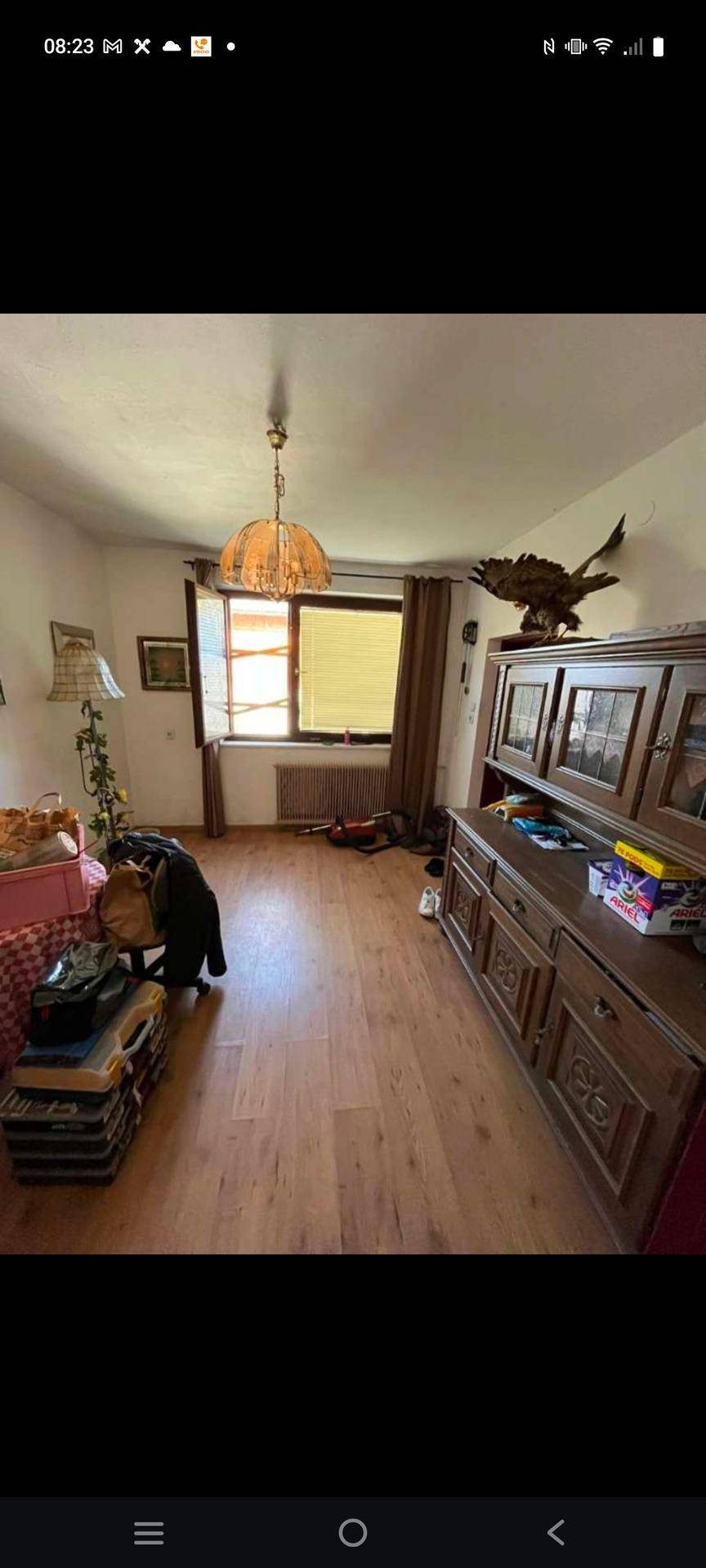 Geräumiger Raum mit Holzboden, großem Holzschrank und einem Fenster für viel Tageslicht.