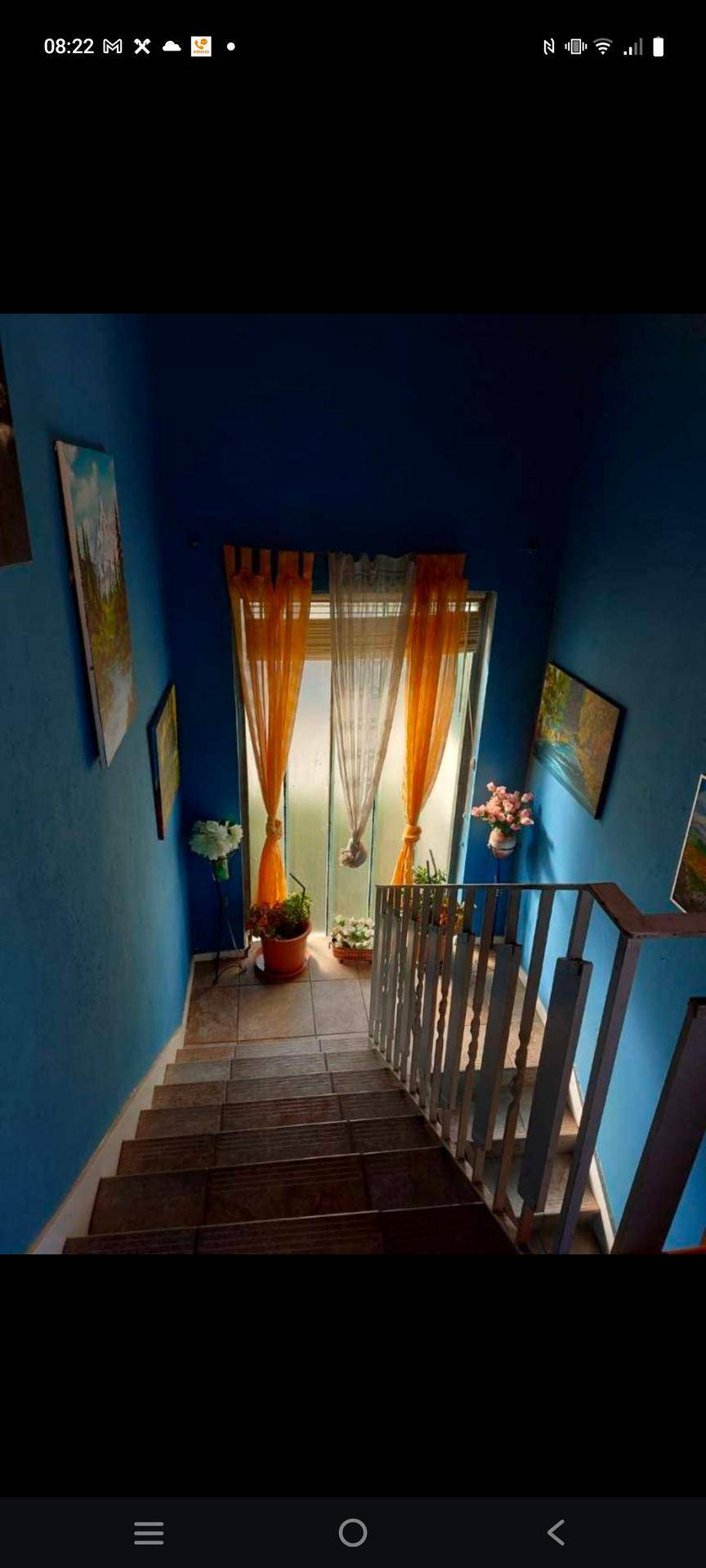 Treppenhaus mit leuchtend blauen Wänden und einem Fenster, das den Bereich erhellt.
