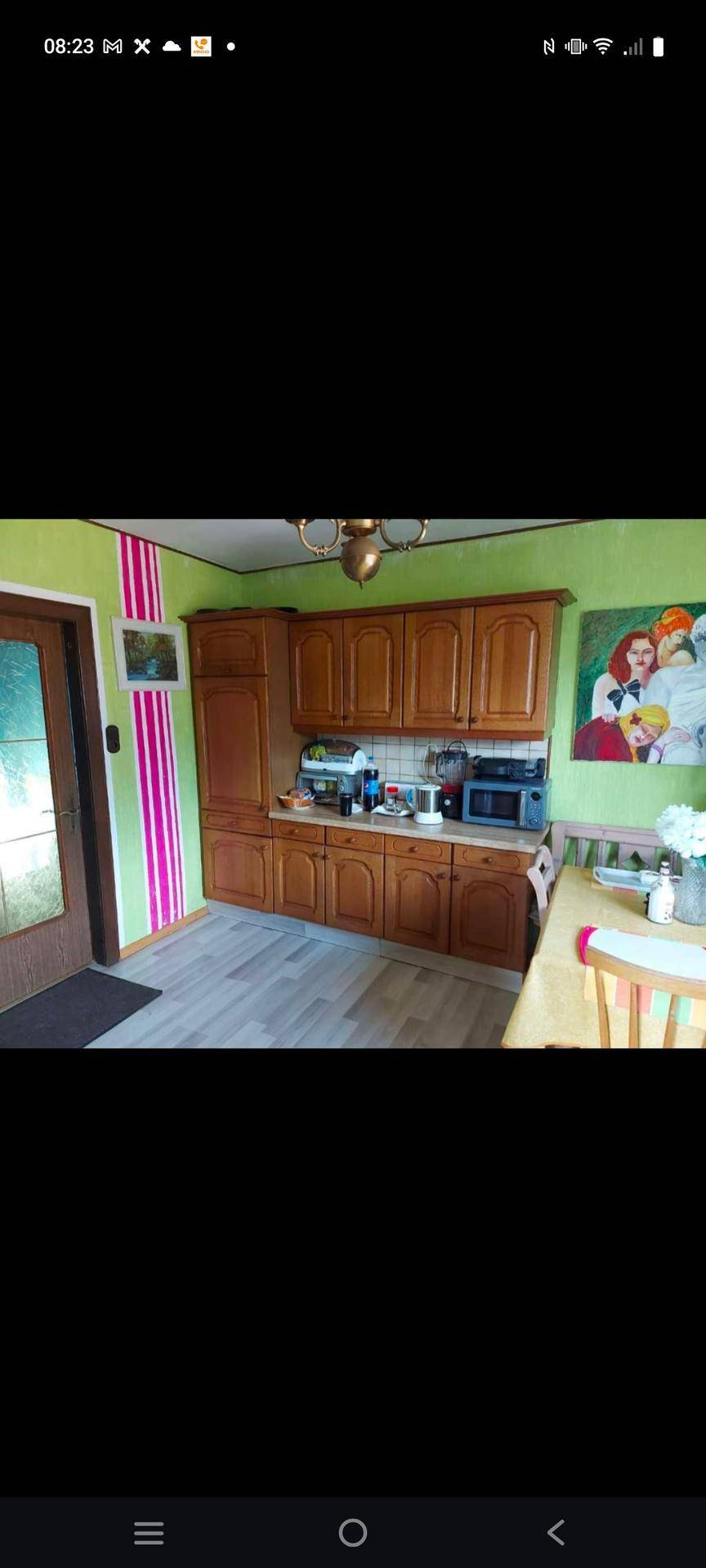 Küche mit Holzschränken, gestreifter Tapete und modernen Geräten, funktional und farbenfroh.