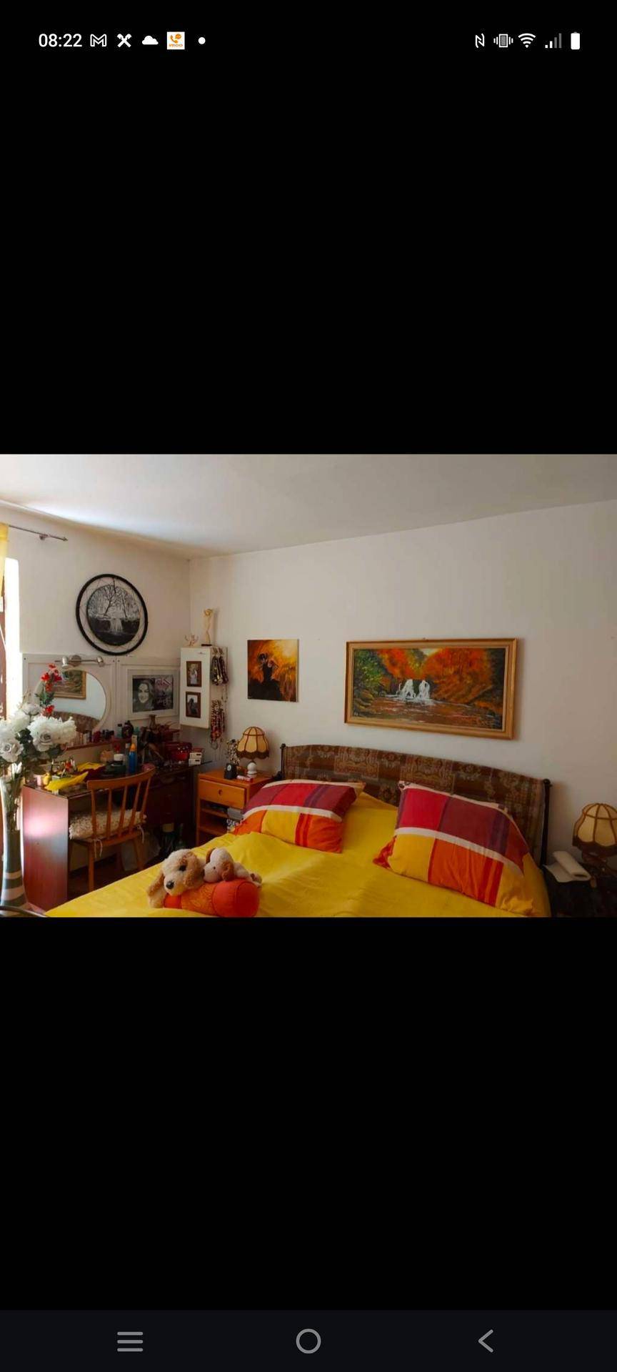 Helles Schlafzimmer mit Doppelbett, weißen Wänden und einem kleinen Arbeitsbereich am Fenster.