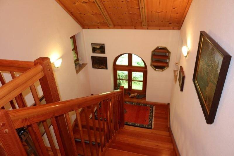 Hölzernes Treppenhaus mit rustikalem Charme und einem Bogenfenster, das Licht hereinlässt.