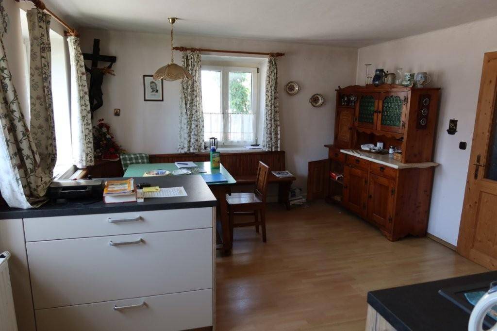 Gemütliche Wohnküche mit traditionellen Holzmöbeln und Blick ins Grüne.