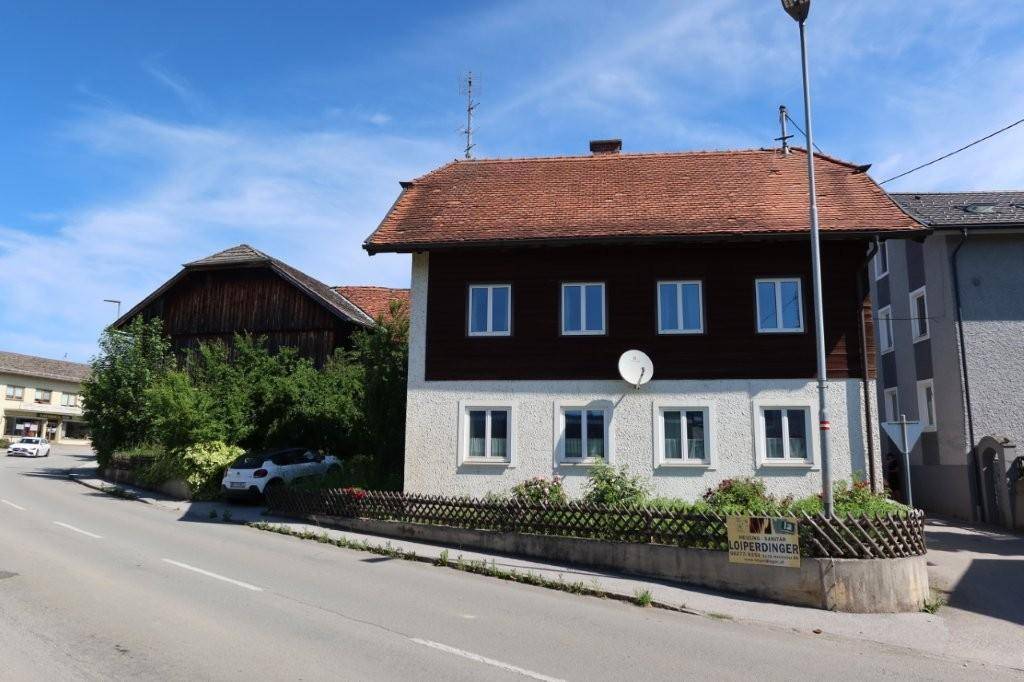 Ansicht des Wohnhauses von der Straße mit angrenzendem Nebengebäude und viel Grün.