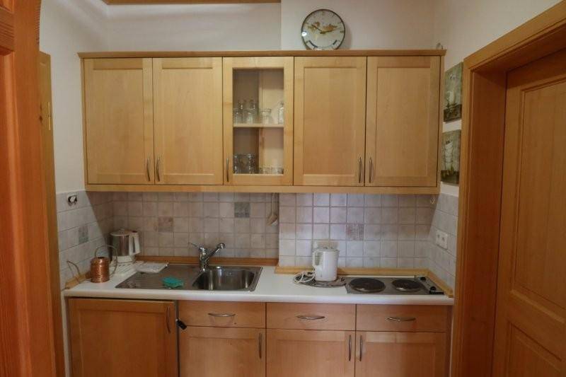 Kleine Kochnische mit hellen Holzschränken, Spüle und zwei Kochplatten.