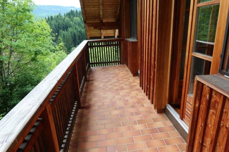 Geräumiger Balkon mit Holzverkleidung und weitem Blick über die bewaldete Landschaft.