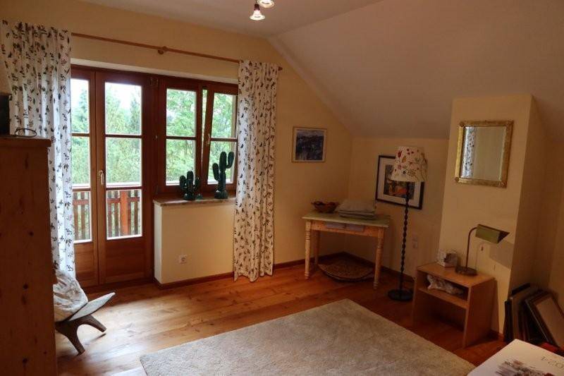 Helles Schlafzimmer mit Holzboden, Dachschräge und direktem Zugang zu einem Balkon.