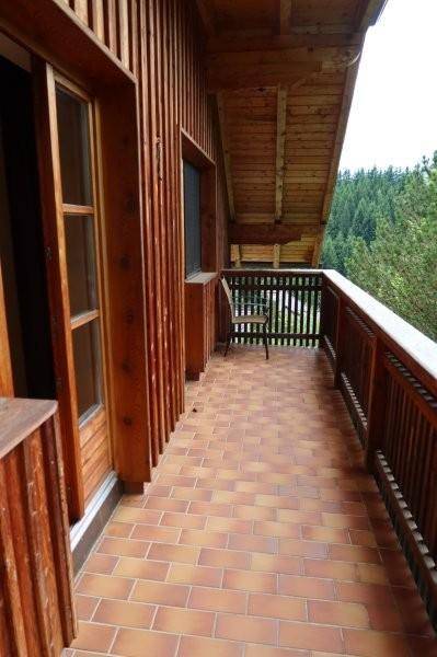 Langer Balkon mit Terrakottafliesen und Holzgeländer, bietet einen weiten Blick ins Grüne.
