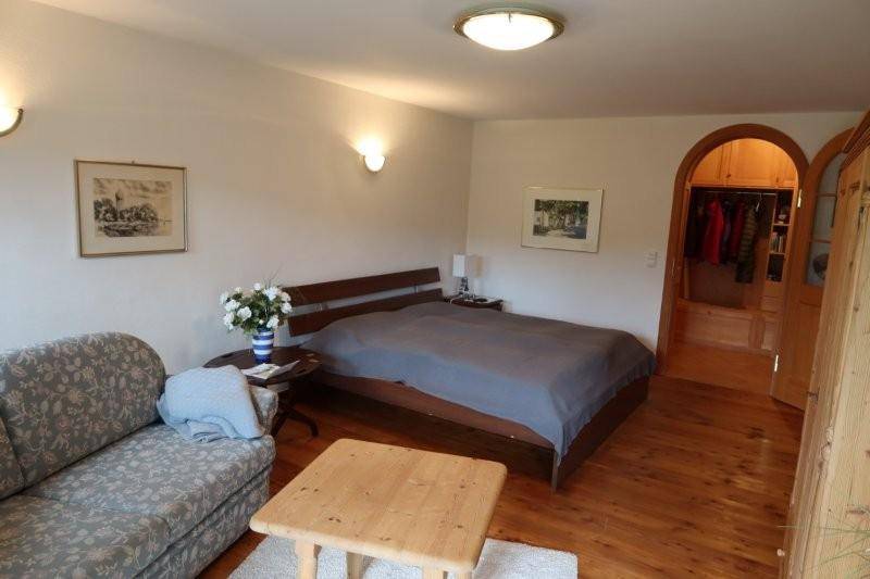 Gemütliches Schlafzimmer mit Holzboden, Doppelbett und Zugang zu einem begehbaren Kleiderschrank.
