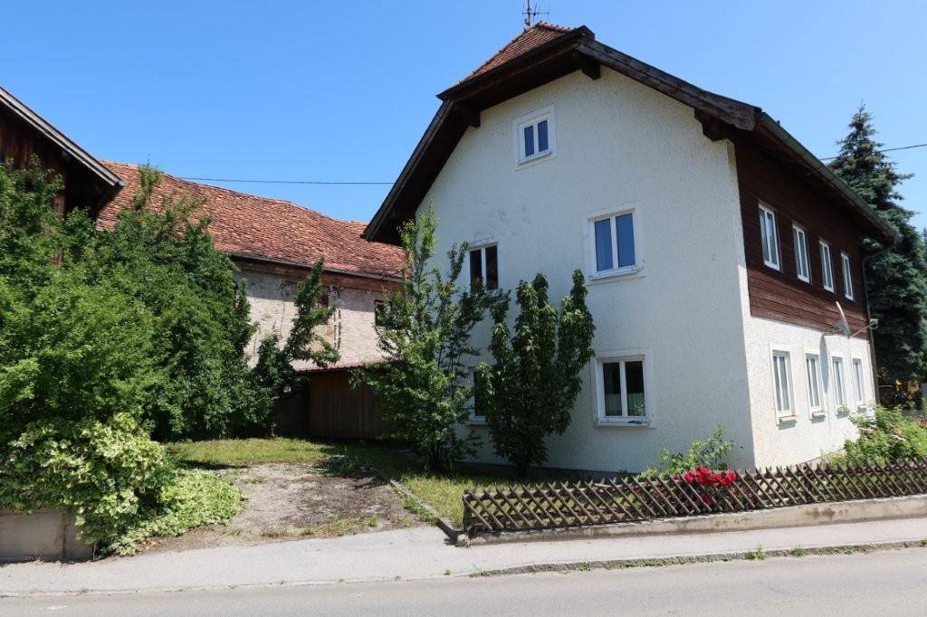 Rückansicht des Wohnhauses mit weißer Fassade und angrenzendem, älteren Gebäude.