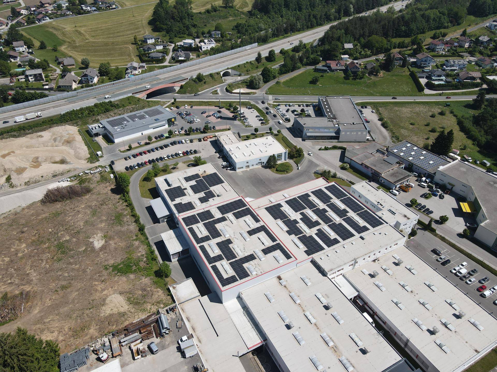 Überblick über den Gewerbepark mit Solarmodulen auf den Dächern und angrenzender Autobahn.