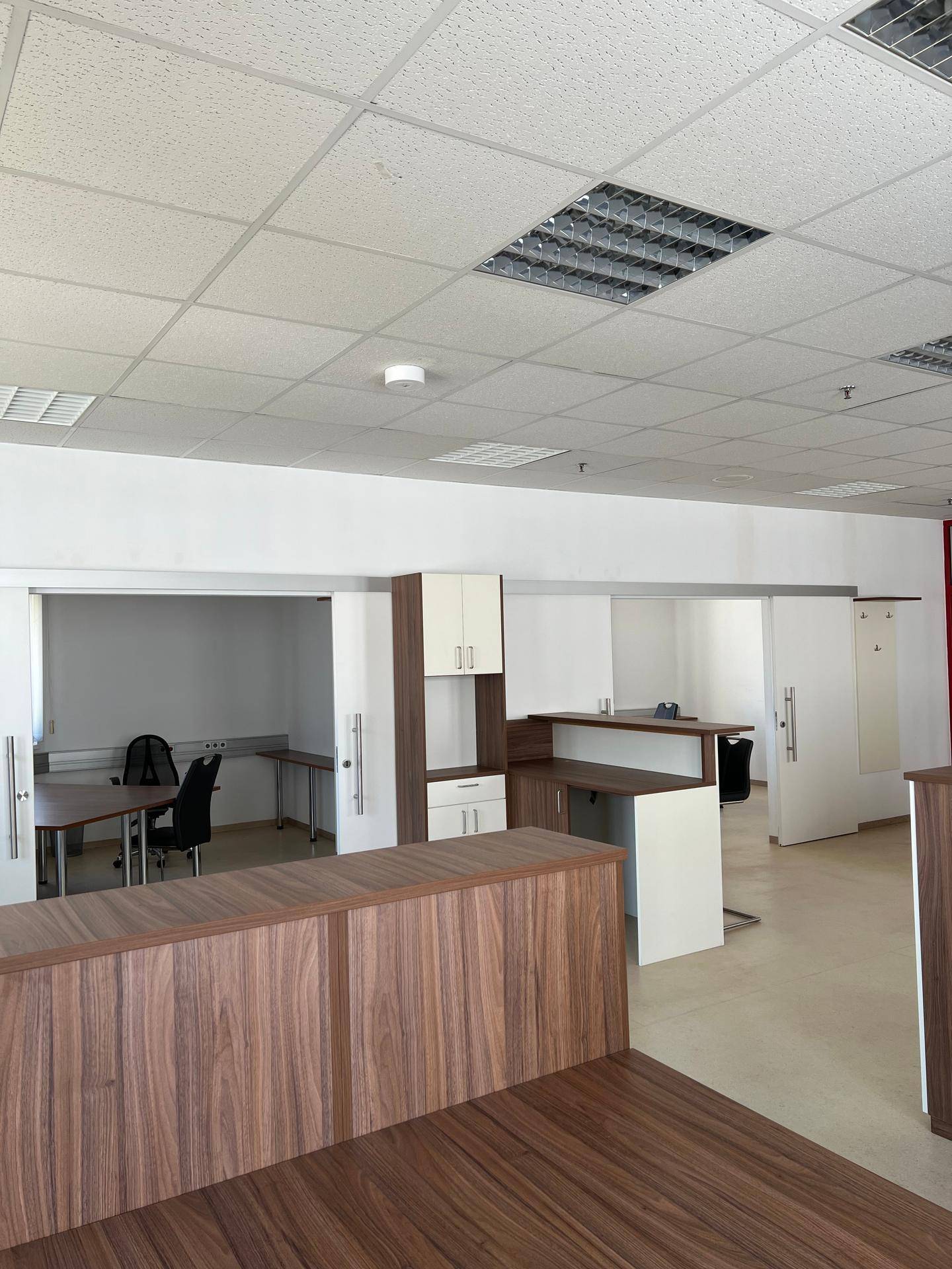 Bürobereich mit integrierten Schränken, Holzelementen und Zugang zu einem separaten Arbeitszimmer.