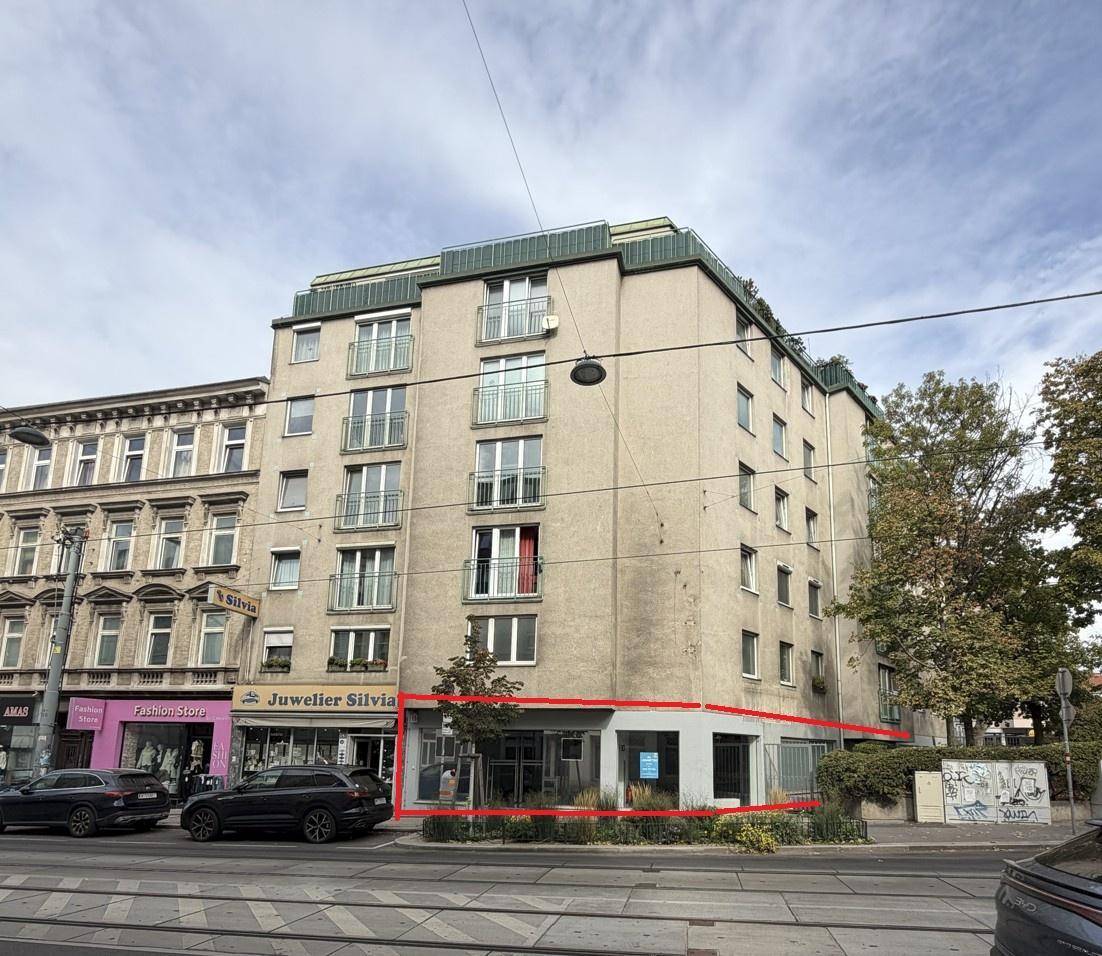 Gesamtansicht eines Mehrfamilienhauses mit Geschäftsräumen im Erdgeschoss, rot umrandet.
