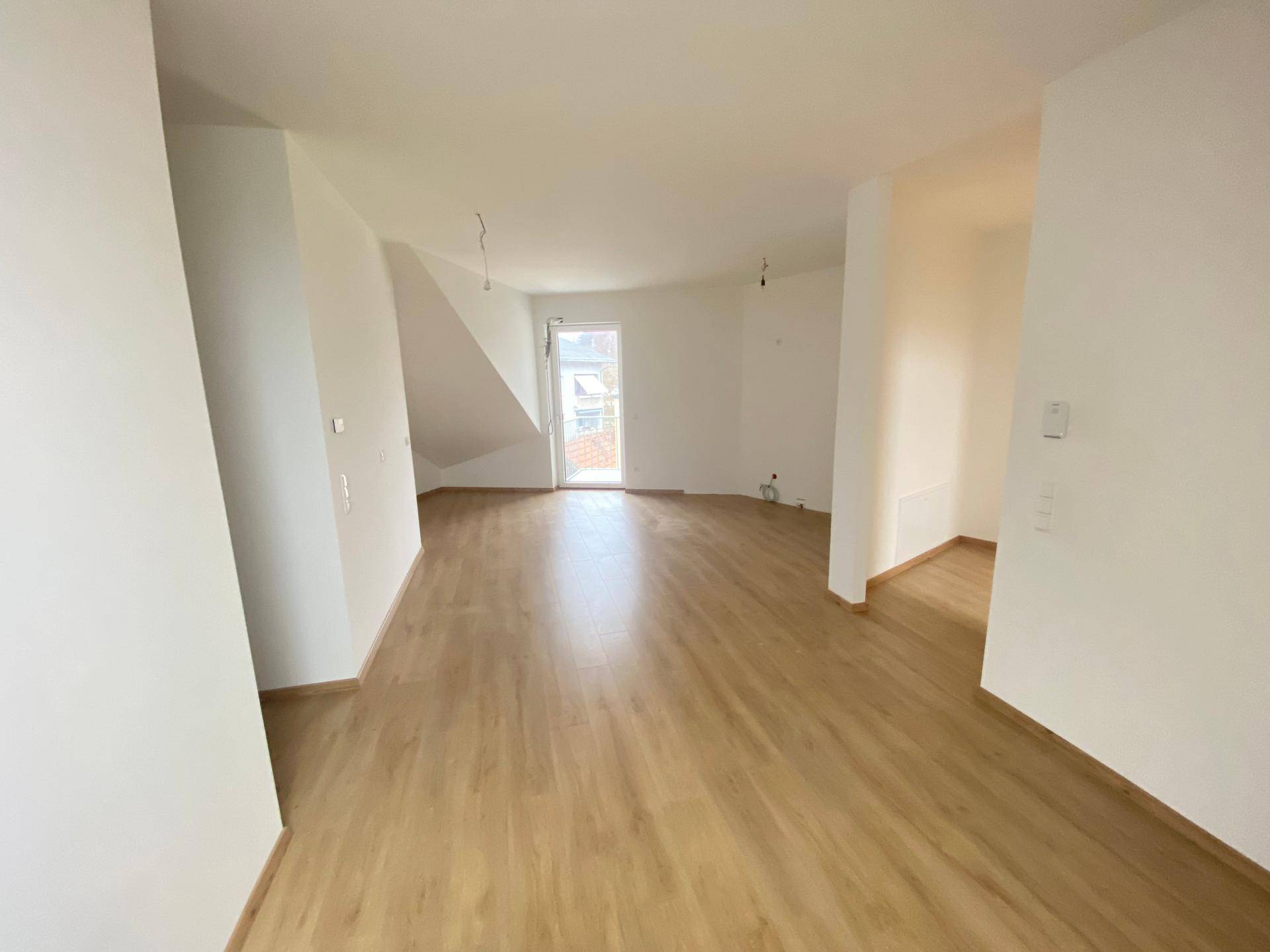Geräumiges Zimmer im Dachgeschoss mit Laminatboden und Zugang zu einem Balkon oder einer Terrasse.