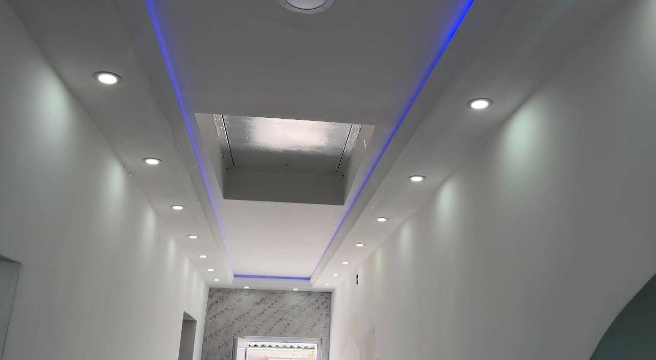 Moderner Deckenbereich mit integrierten LED-Spots und blauer Akzentbeleuchtung.