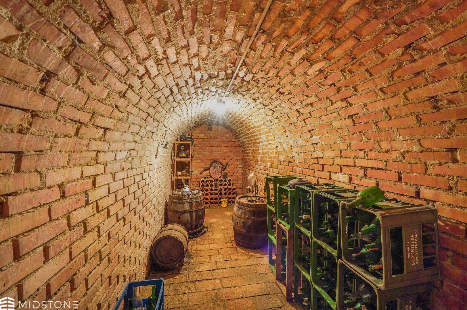 Historischer Weinkeller mit Ziegelgewölbe, Holzfässern und Weinregalen.