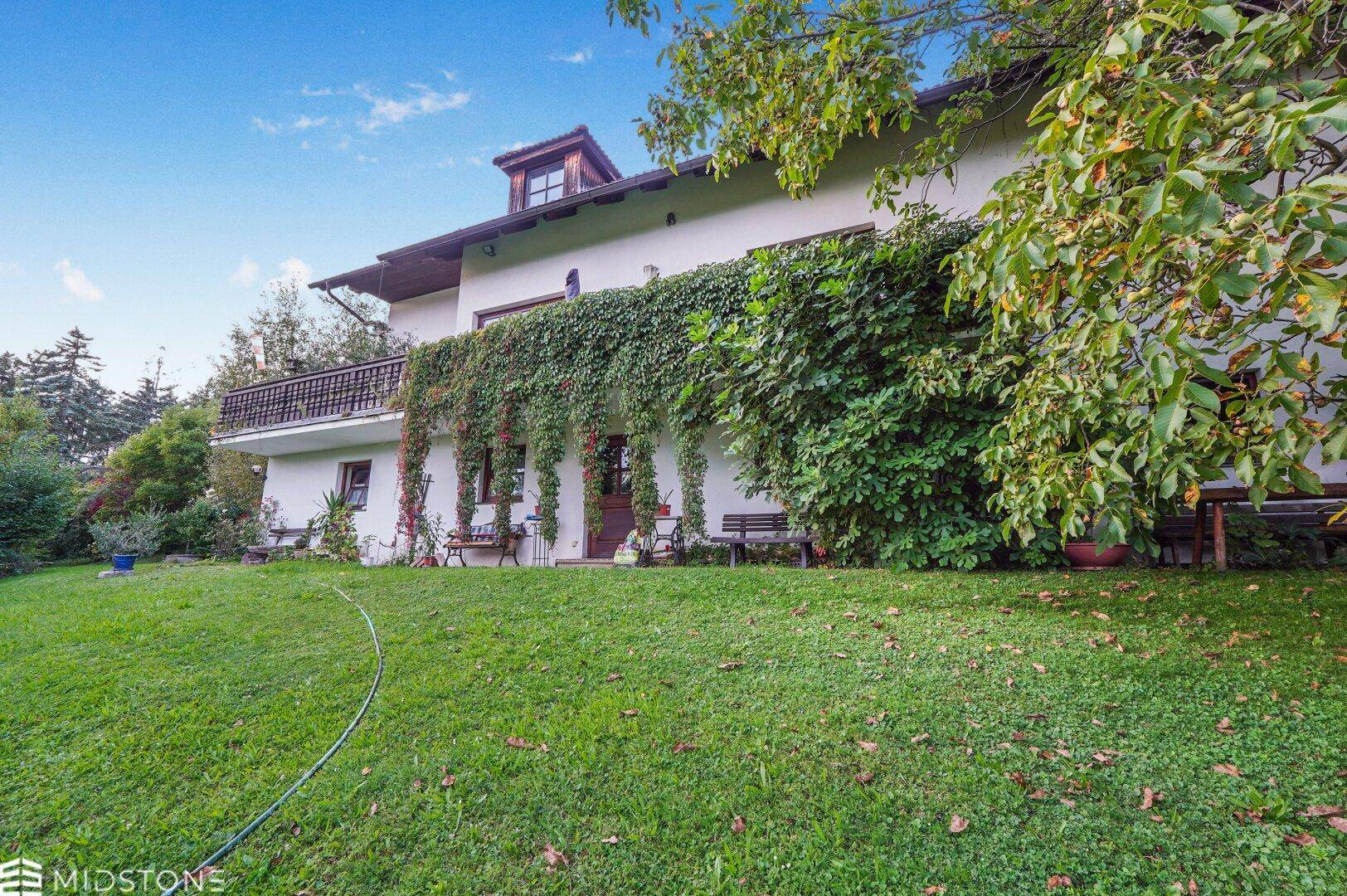 Rückansicht des Hauses mit großem Garten und üppiger Begrünung an der Fassade.