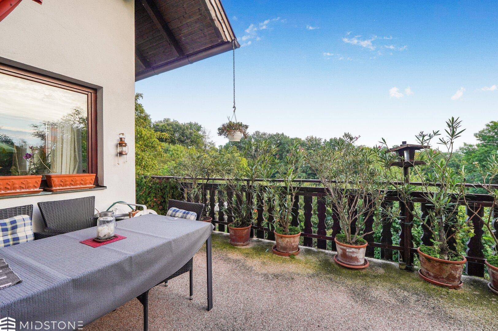 Balkon mit Esstisch und Pflanzen, bietet einen weiten Blick ins Grüne.
