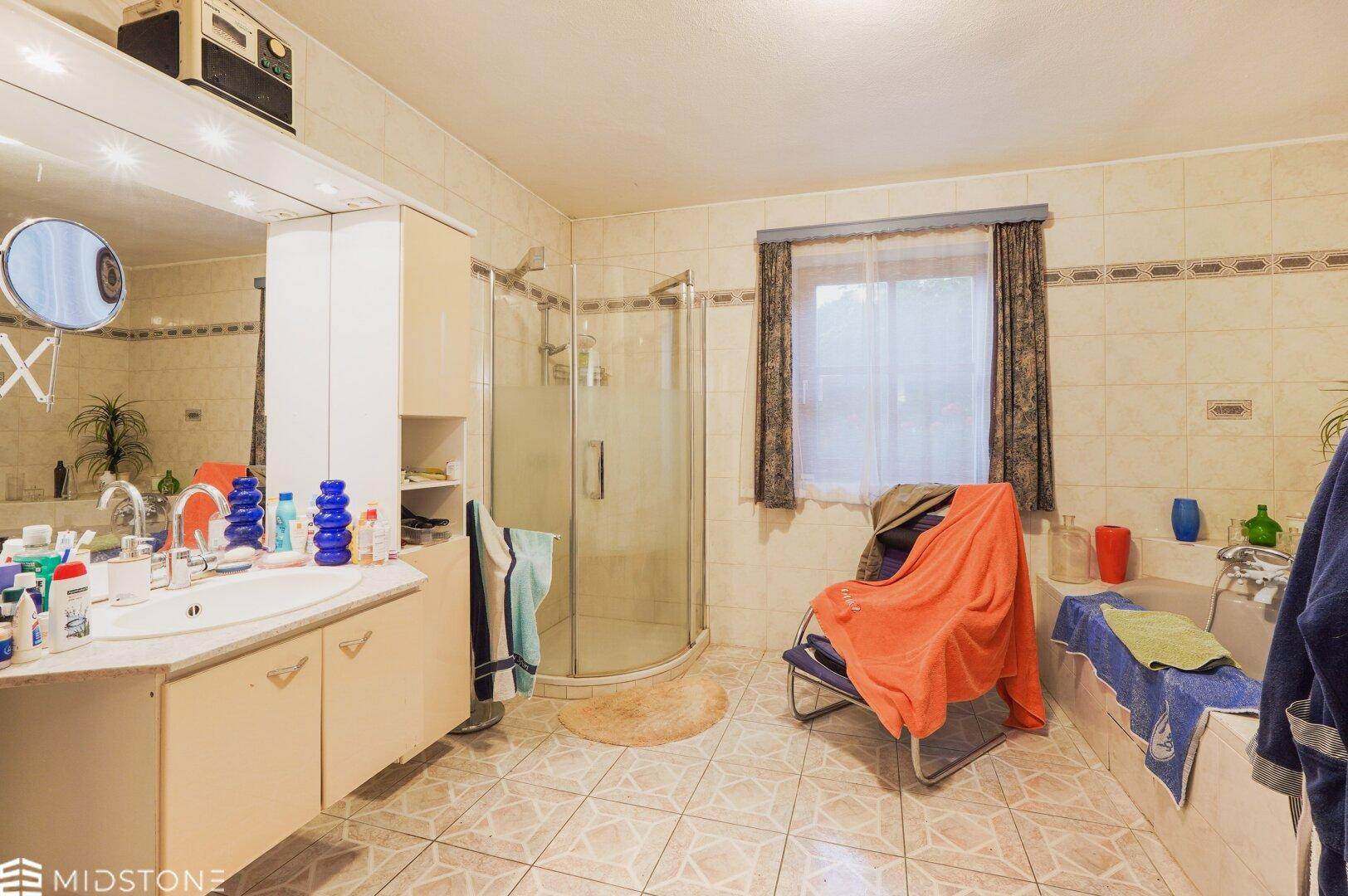 Badezimmer mit Duschkabine, Badewanne, Einzelwaschbecken und Fliesen an Wänden und Boden.