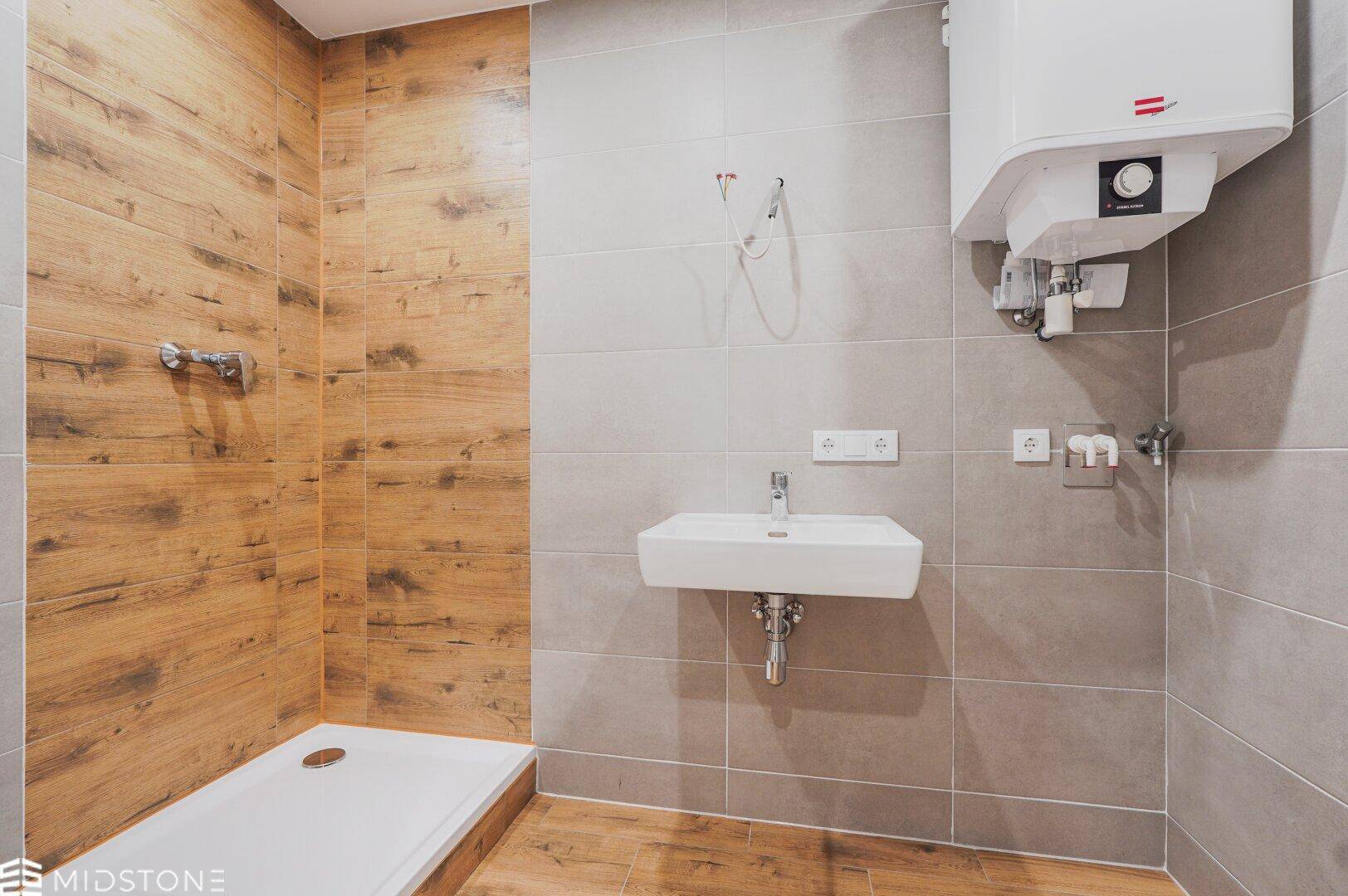 Modernes Badezimmer mit Duschbereich, Waschbecken und Wandfliesen in Holzoptik.