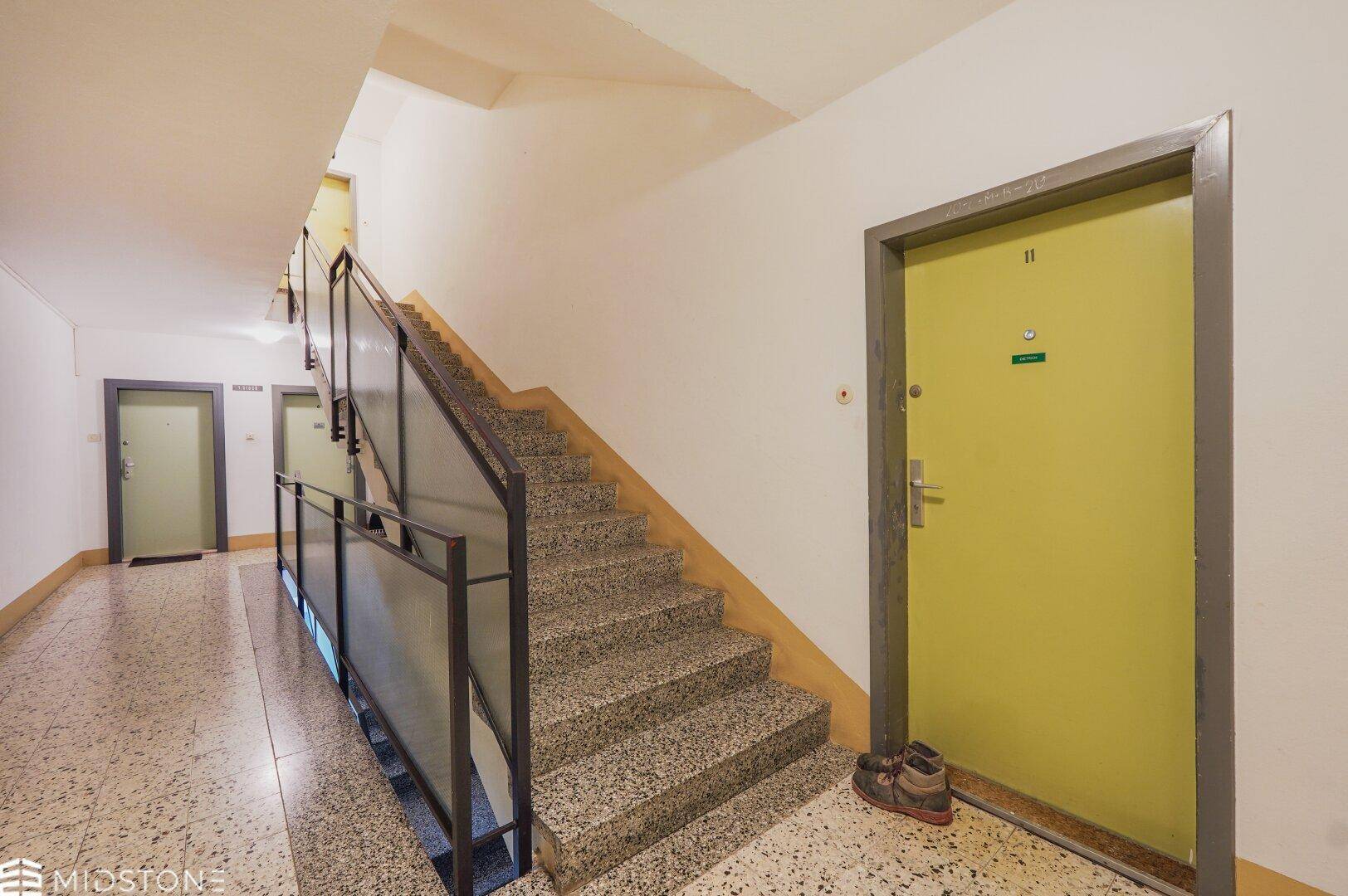 Treppenhaus mit Terrazzoboden und Metallgeländer, führt zu den verschiedenen Wohneinheiten.