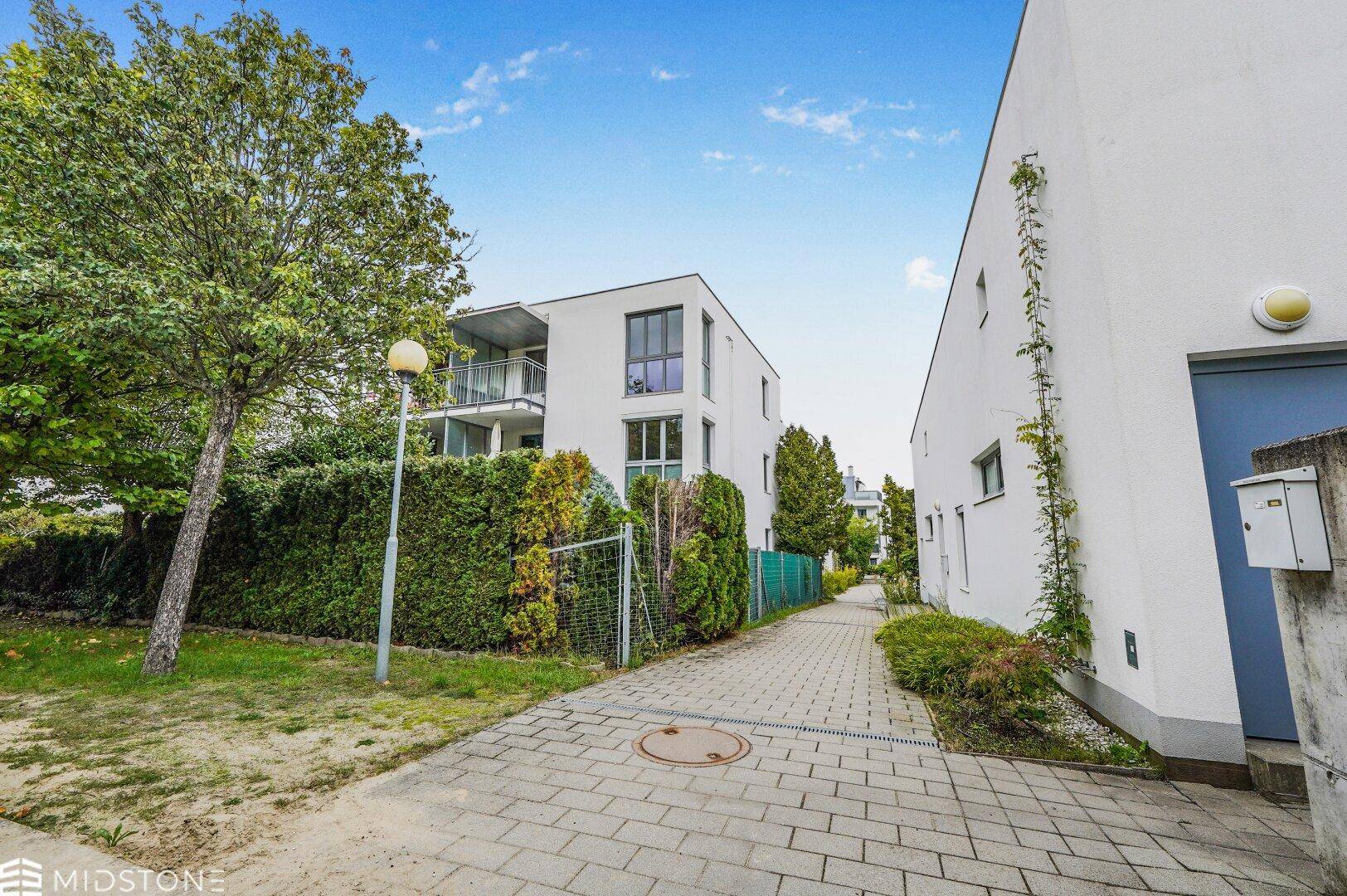Blick auf die Wohnanlage mit gepflegten Grünflächen und einem gepflasterten Fußweg.