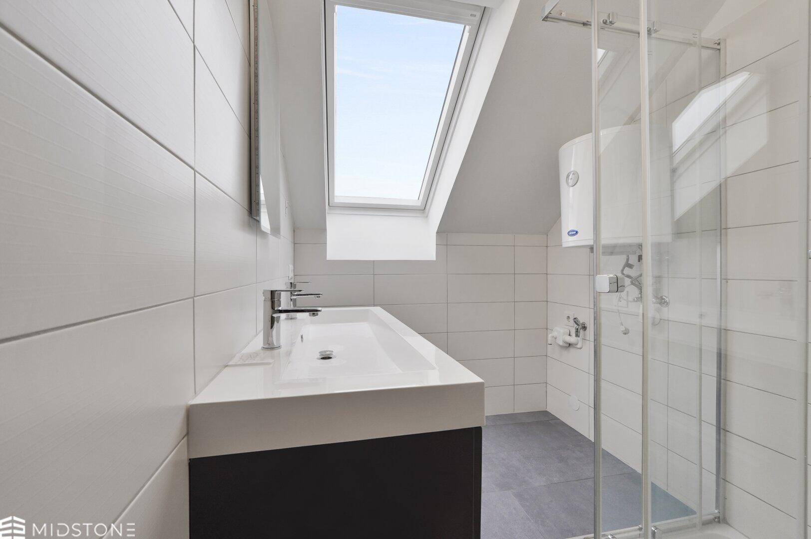 Modernes Badezimmer mit weiß gefliesten Wänden, großem Dachfenster und Duschkabine.